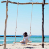 A girl seated on the 'Yurari' Driftwood Swing