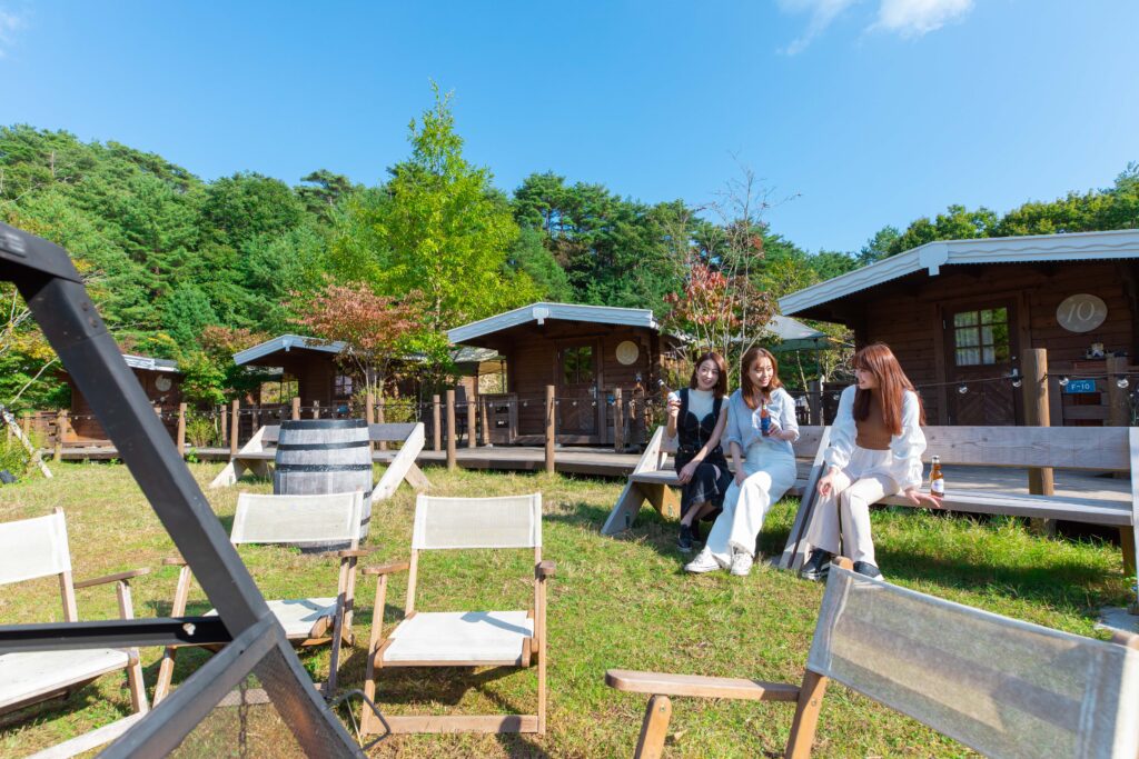 People drinking on a bench in front of cabins