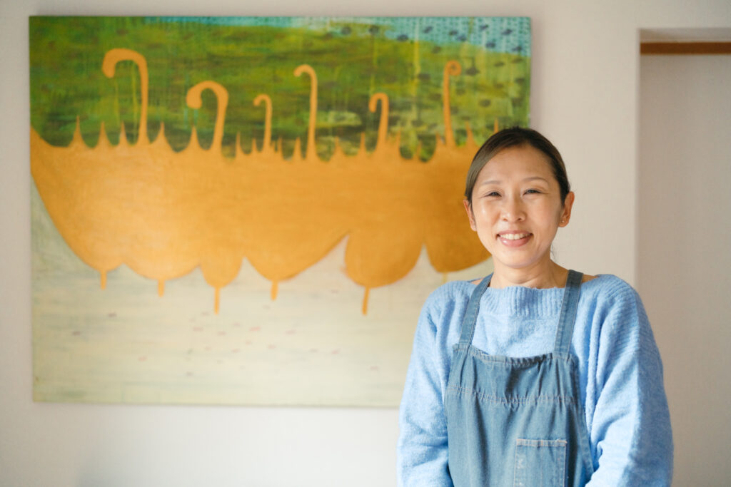 A lady smiling in front of a painting