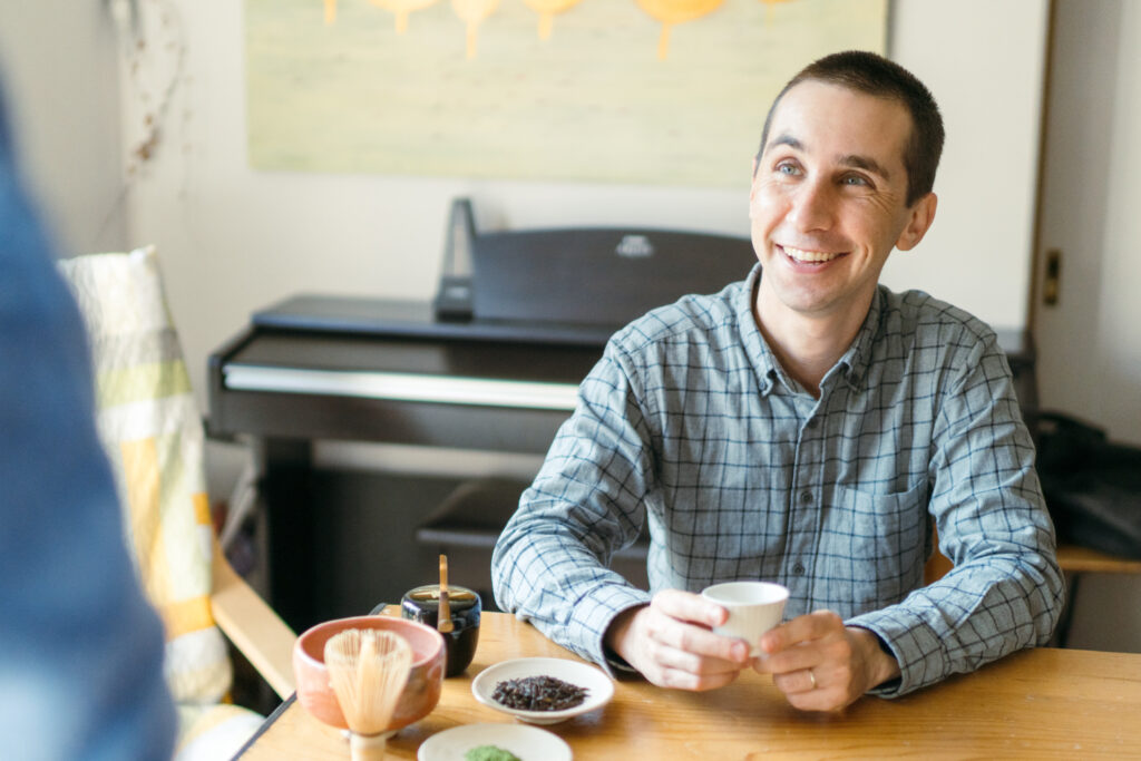 A man smiling while drinking tea