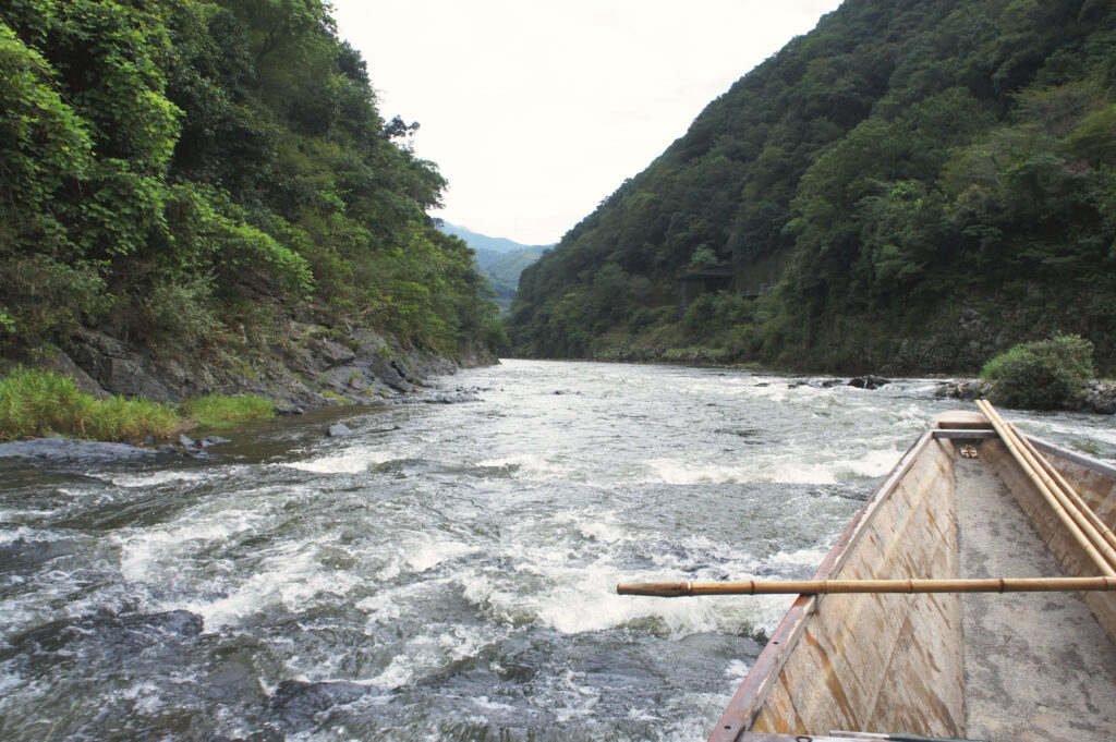 Wooden boat in a river flanked by green hills