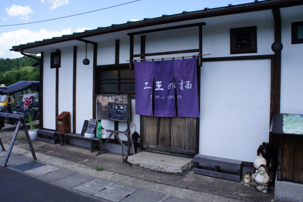 The charming storefront of Nio no Sumika, a traditional Japanese building with a purple noren curtain at its entrance.