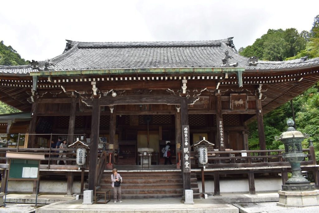 Weathered wooden exterior of Yoshimine-dera Temple in Kyoto with visitors coming to pray.