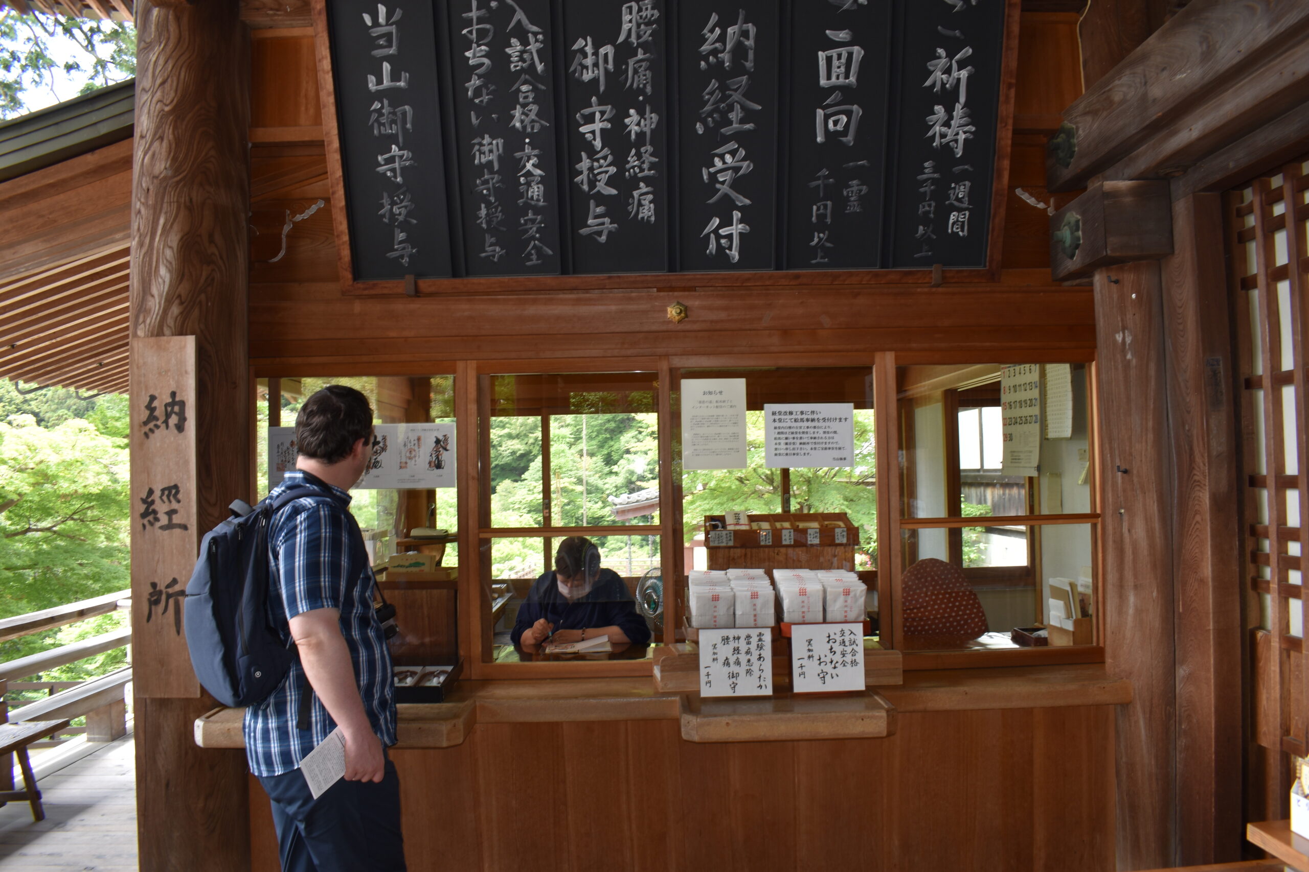 Tourist waiting for the temple priest to place a goshuin stamp in his goshuincho.